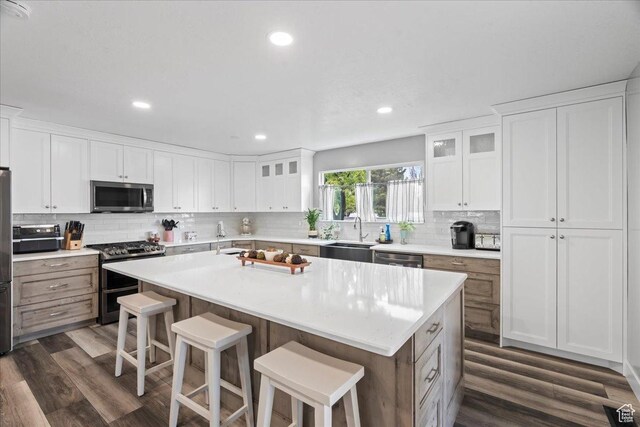 2490 W 12195 S, Riverton, UT 84065 - kitchen with stainless steel appliances, dark wood-style floors, tasteful backsplash, a breakfast bar area, and recessed lighting