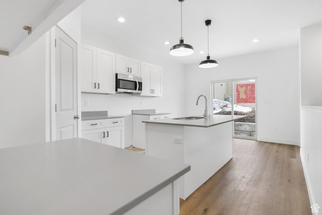 271 N 1160 N Unit 32, Tooele, UT 84074 - kitchen with white cabinets, stainless steel microwave, a sink, and an island with sink