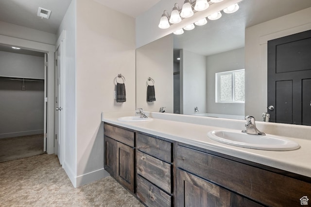 full bathroom featuring double vanity, visible vents, a walk in closet, and a sink