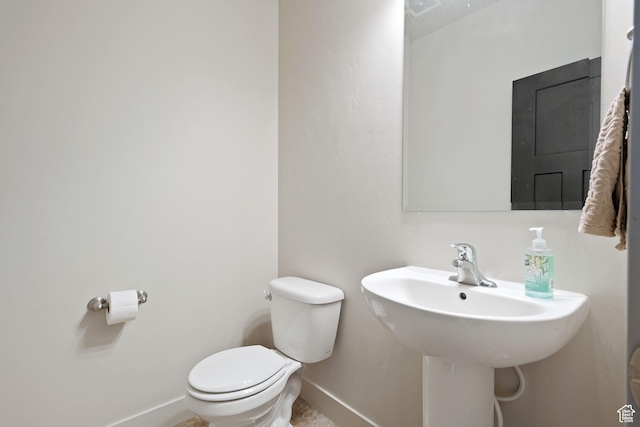 half bath featuring visible vents, a sink, toilet, and baseboards