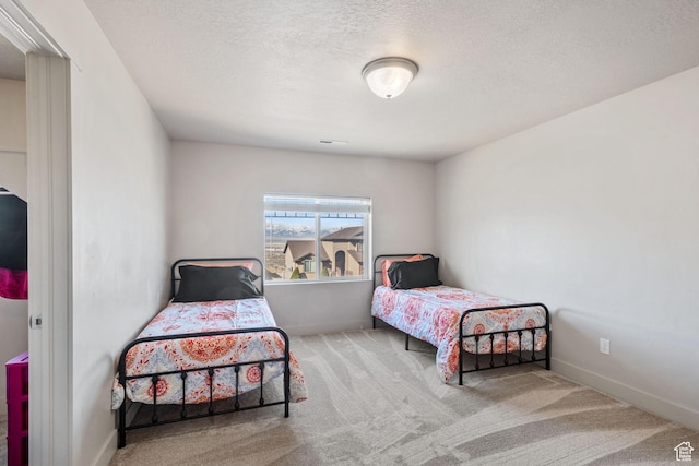 bedroom with carpet, baseboards, and a textured ceiling