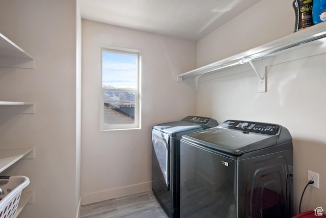 laundry room with laundry area, light wood-type flooring, washing machine and clothes dryer, and baseboards