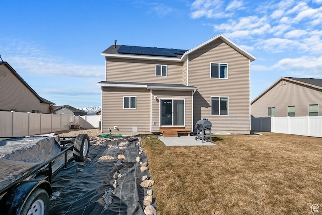 rear view of house featuring entry steps, solar panels, a patio, a fenced backyard, and a yard