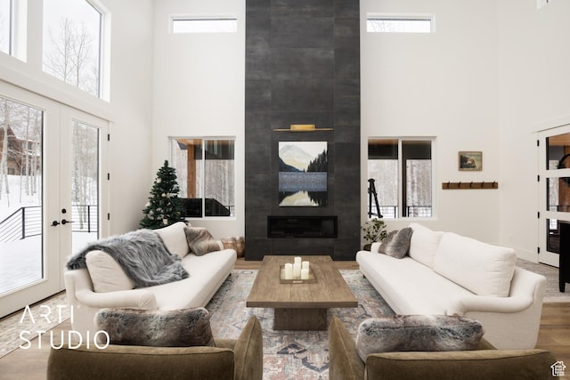 living room with visible vents, a tile fireplace, wood finished floors, a high ceiling, and french doors