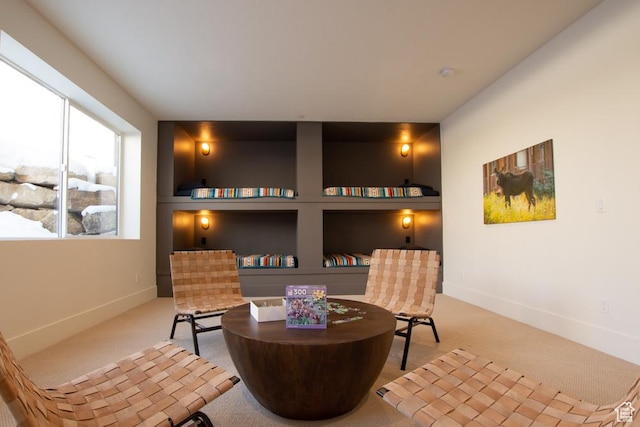 sitting room featuring carpet floors, built in shelves, and baseboards