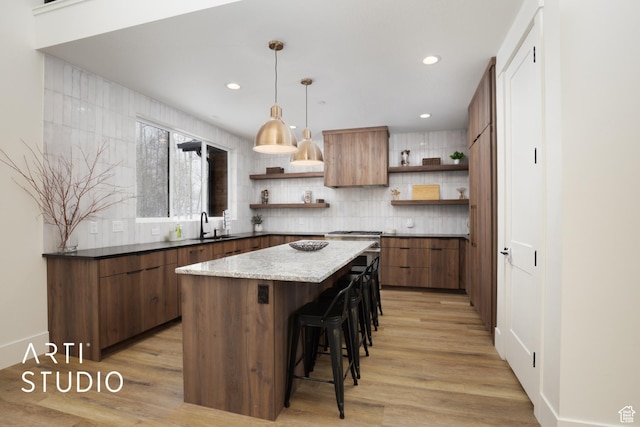 kitchen featuring light wood-style floors, a kitchen island, open shelves, and a sink