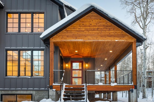 snow covered rear of property with a porch and board and batten siding