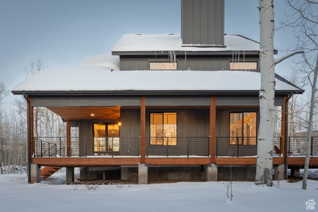 snow covered house featuring covered porch