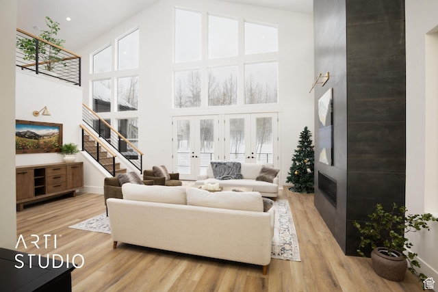 living room with french doors, stairway, a high ceiling, and wood finished floors