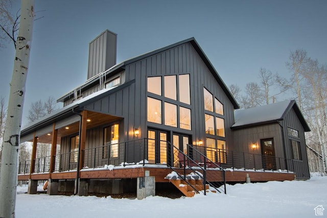 snow covered rear of property featuring board and batten siding