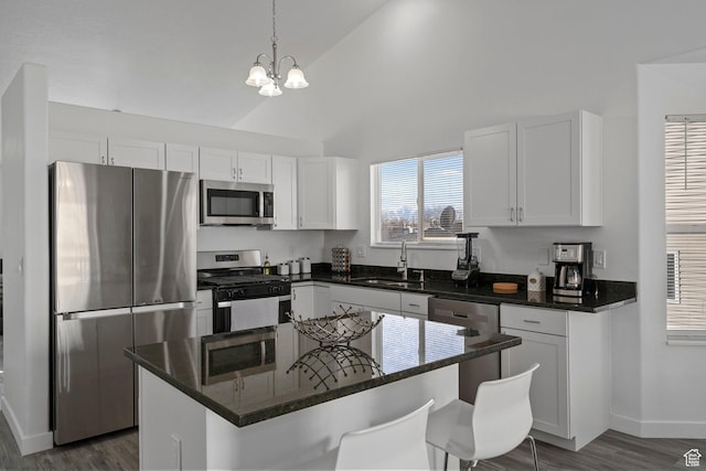 kitchen featuring white cabinets, a kitchen island, appliances with stainless steel finishes, dark wood-style flooring, and a sink