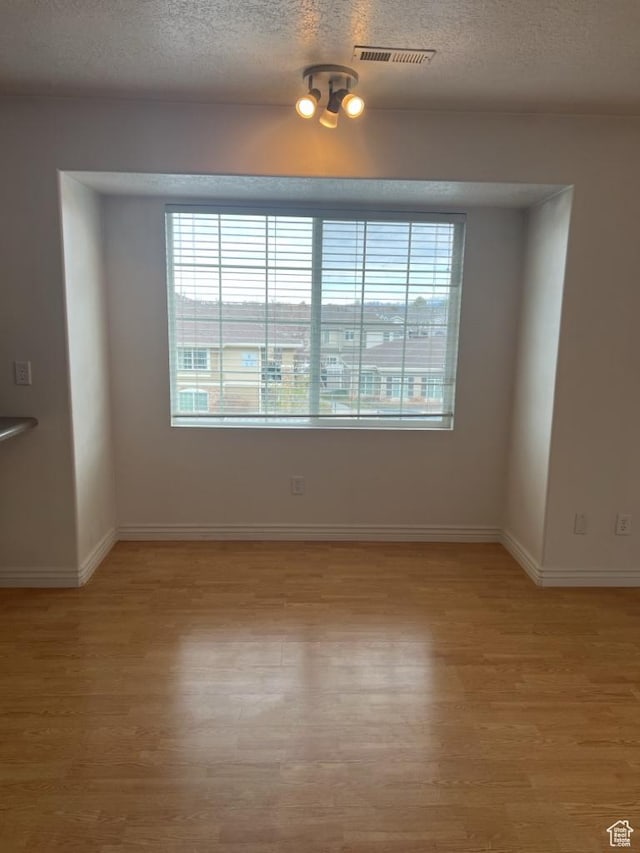196 E Spencer Peak Way S Unit D9, Draper, UT 84020 - spare room featuring light wood-type flooring, plenty of natural light, visible vents, and a textured ceiling