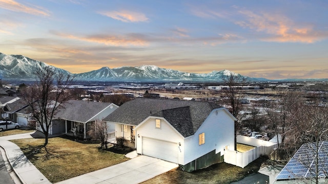 view of front of home featuring driveway, a garage, a shingled roof, fence, and a mountain view