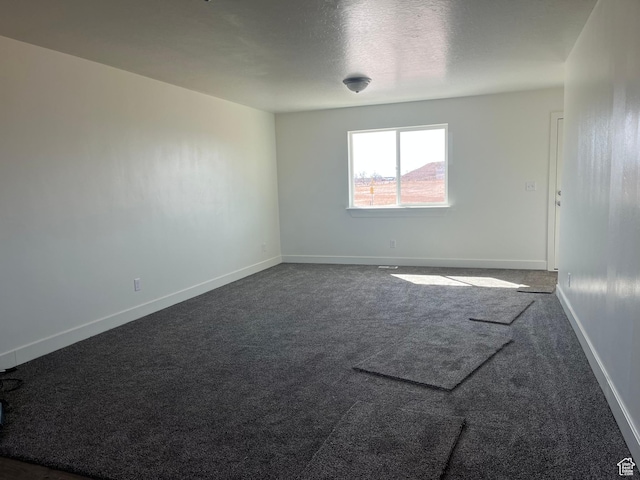 1943 S State St, Roosevelt, UT 84066 - spare room featuring baseboards, a textured ceiling, and dark carpet