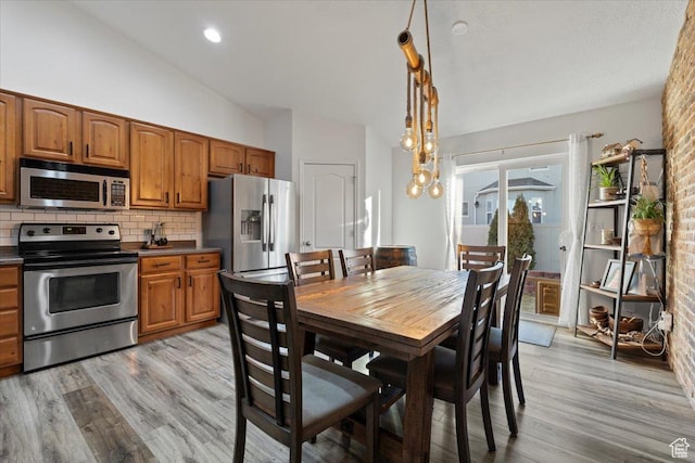 5009 W Greenstreak Dr, Riverton, UT 84096 - kitchen with brown cabinetry, decorative backsplash, vaulted ceiling, stainless steel appliances, and light wood-type flooring