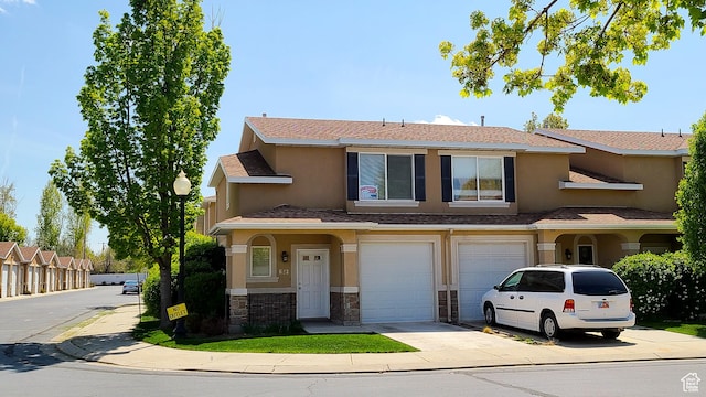 view of front facade with concrete driveway, stone siding, stucco siding, and a garage