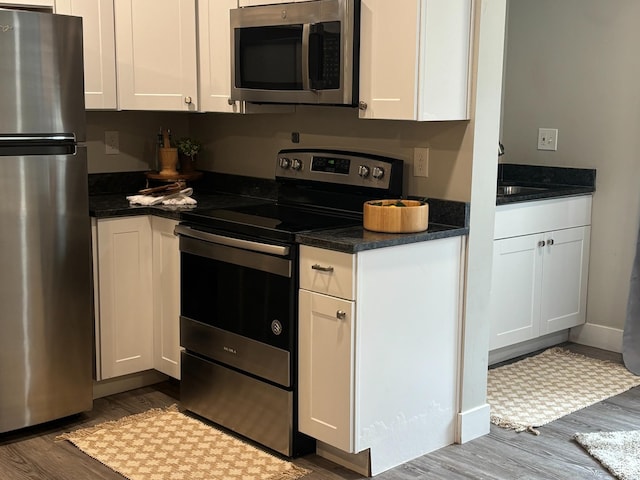 130 S 1300 E Unit 314, Salt Lake City, UT 84102 - kitchen featuring appliances with stainless steel finishes, wood finished floors, white cabinetry, dark countertops, and a sink