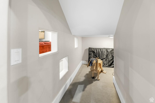 hallway with lofted ceiling, carpet flooring, and baseboards