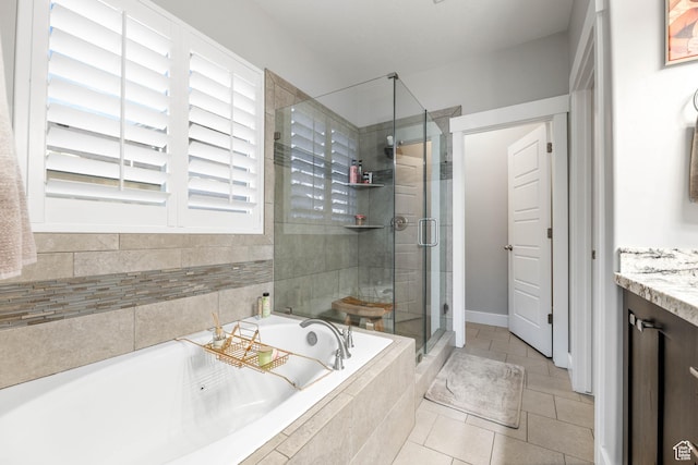 bathroom featuring a stall shower, tile patterned flooring, a garden tub, and vanity