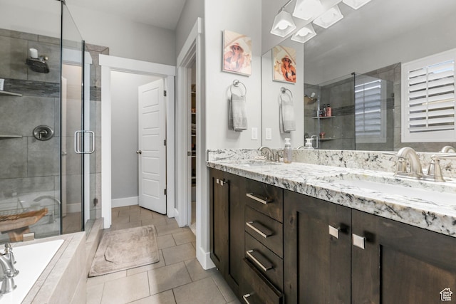 bathroom featuring tile patterned flooring, a relaxing tiled tub, a sink, a shower stall, and double vanity