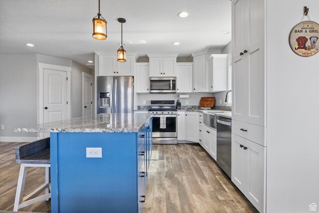 180 S Main St, Fayette, UT 84630 - kitchen featuring white cabinetry, a kitchen bar, appliances with stainless steel finishes, and wood finished floors