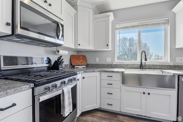 180 S Main St, Fayette, UT 84630 - kitchen with stainless steel appliances, dark wood-style flooring, a sink, white cabinets, and light stone countertops