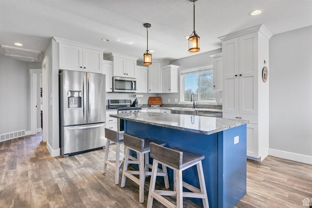 180 S Main St, Fayette, UT 84630 - kitchen with stainless steel appliances, visible vents, light wood-style floors, a sink, and a kitchen island
