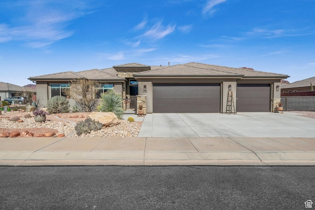 530 W Cougar Way, Ivins, UT 84738 - prairie-style house with concrete driveway, stucco siding, fence, stone siding, and a garage