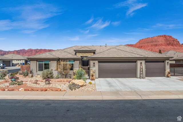 530 W Cougar Way, Ivins, UT 84738 - prairie-style house with stucco siding, fence, stone siding, a mountain view, and a garage