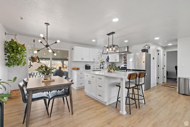 kitchen with light countertops, freestanding refrigerator, white cabinetry, and light wood-style flooring