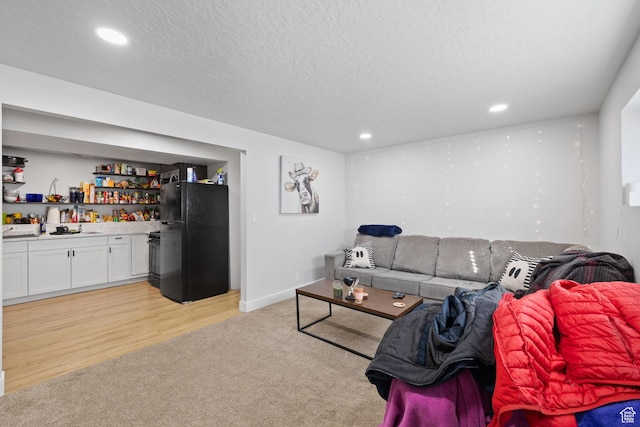 living area with recessed lighting, light colored carpet, light wood-style floors, a textured ceiling, and a bar