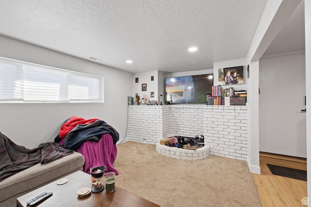 living room featuring a textured ceiling, wood finished floors, visible vents, and baseboards