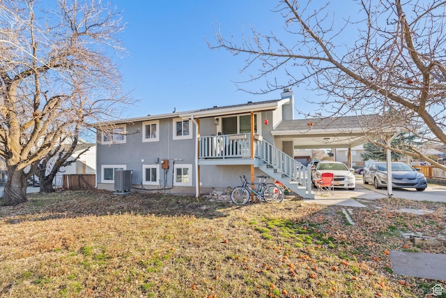 rear view of house with a chimney, stucco siding, fence, an attached carport, and stairs