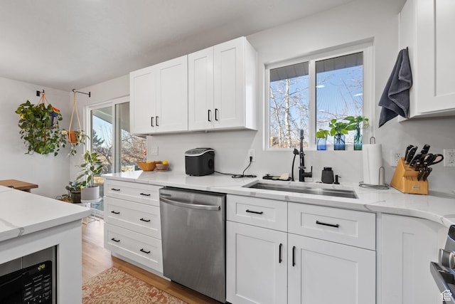 kitchen featuring light wood-type flooring, white cabinets, a sink, and stainless steel dishwasher