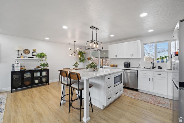 kitchen featuring light wood-style flooring, a kitchen bar, white cabinetry, and stainless steel appliances