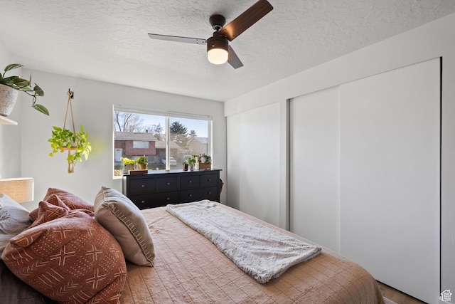 bedroom with multiple closets, ceiling fan, and a textured ceiling