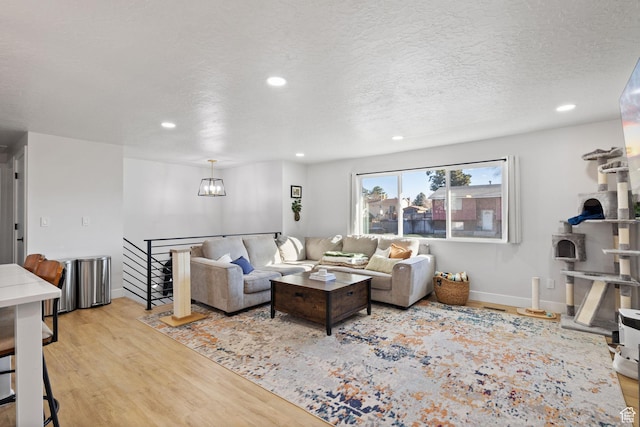 living room with baseboards, wood finished floors, a textured ceiling, a chandelier, and recessed lighting