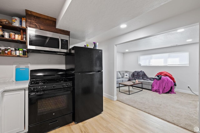 kitchen featuring black appliances, light wood finished floors, light countertops, and baseboards