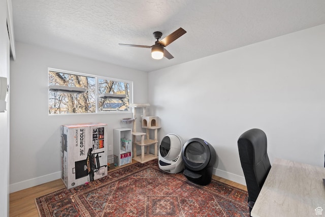 office with a ceiling fan, a textured ceiling, baseboards, and wood finished floors