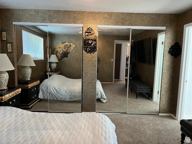 bedroom with two closets, baseboards, and carpet flooring