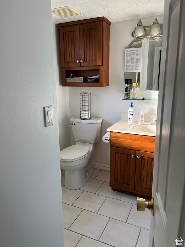 half bath with visible vents, toilet, tile patterned flooring, a textured ceiling, and vanity
