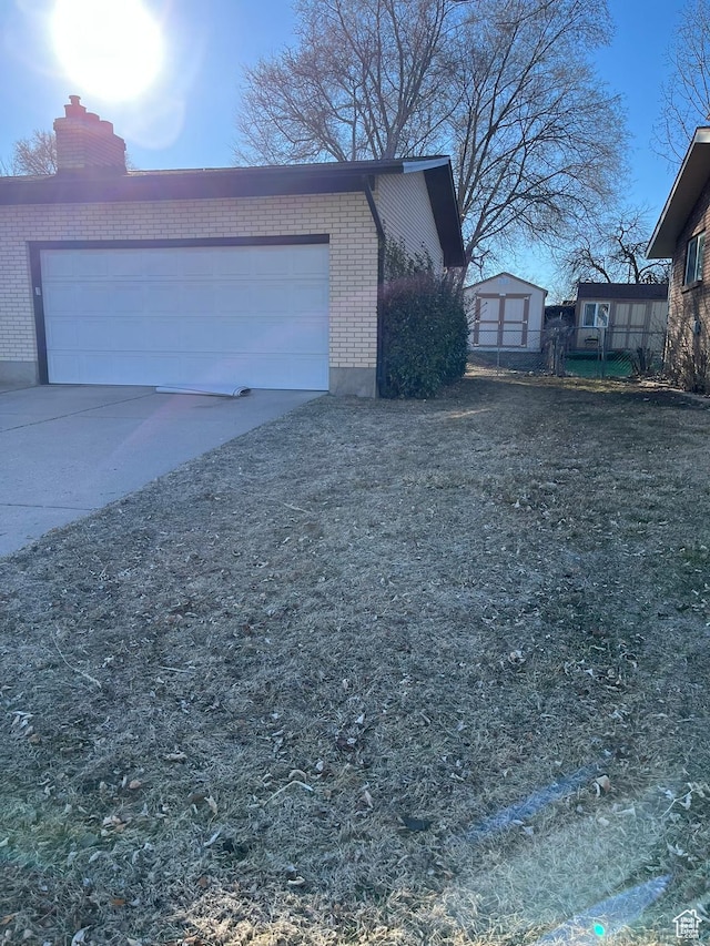 view of home's exterior featuring driveway, brick siding, and a chimney
