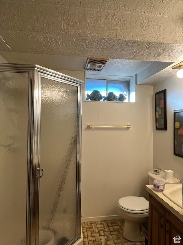 bathroom with toilet, a stall shower, vanity, a textured ceiling, and baseboards
