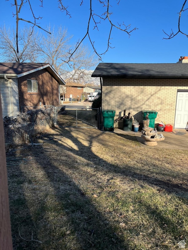 exterior space with a gate, fence, and brick siding