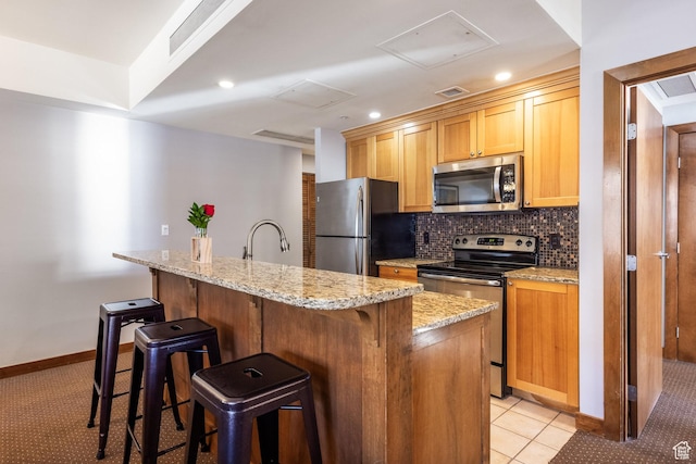 3720 N Sundial Ct Unit C007, Park City, UT 84098 - kitchen featuring tasteful backsplash, visible vents, appliances with stainless steel finishes, a kitchen breakfast bar, and light stone countertops