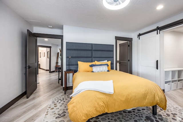 12 Thaynes Canyon Dr, Park City, UT 84060 - bedroom with a barn door, baseboards, light wood-style flooring, and a textured ceiling