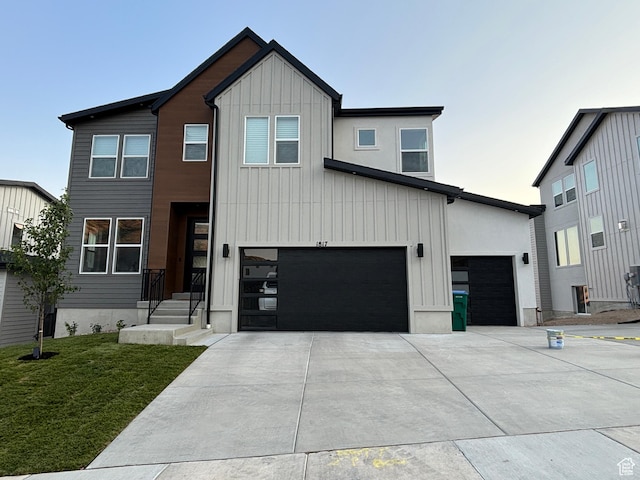 view of front of house featuring a front lawn, an attached garage, board and batten siding, and concrete driveway