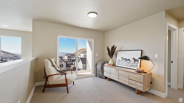 living area featuring light carpet, a healthy amount of sunlight, visible vents, and baseboards