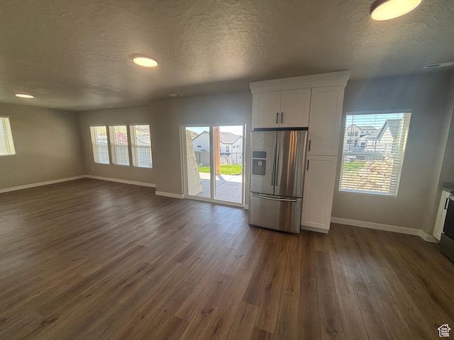 interior space with a textured ceiling, baseboards, and dark wood-style floors