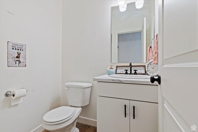 bathroom with toilet, baseboards, wood finished floors, and vanity